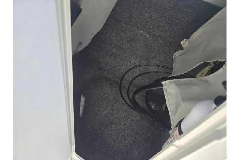 Slide: The Image of Interior storage compartment of a 2011 Yamaha Boats SX240 HO, featuring carpeted flooring and equipment. - 16