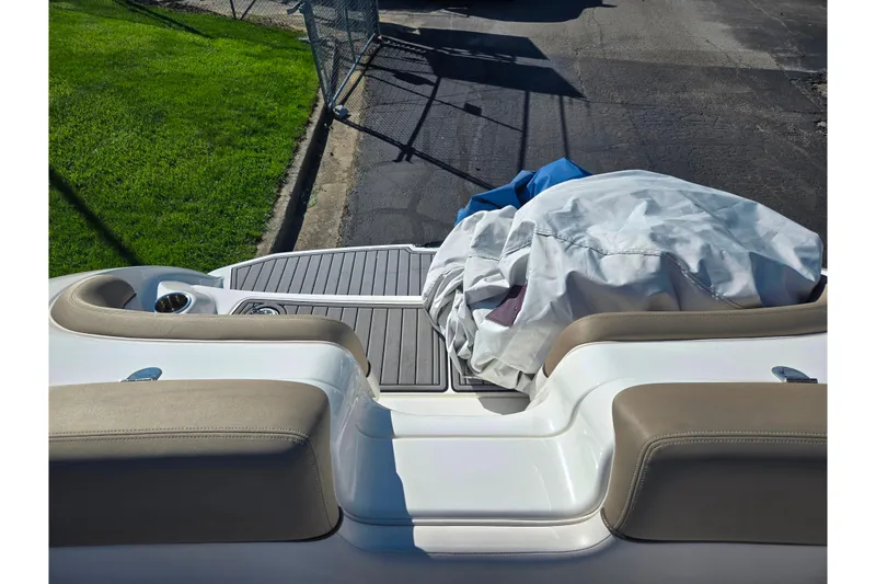 Slide: The Image of 2011 Yamaha Boats SX240 HO rear deck with seating and cover, parked on pavement. - 24