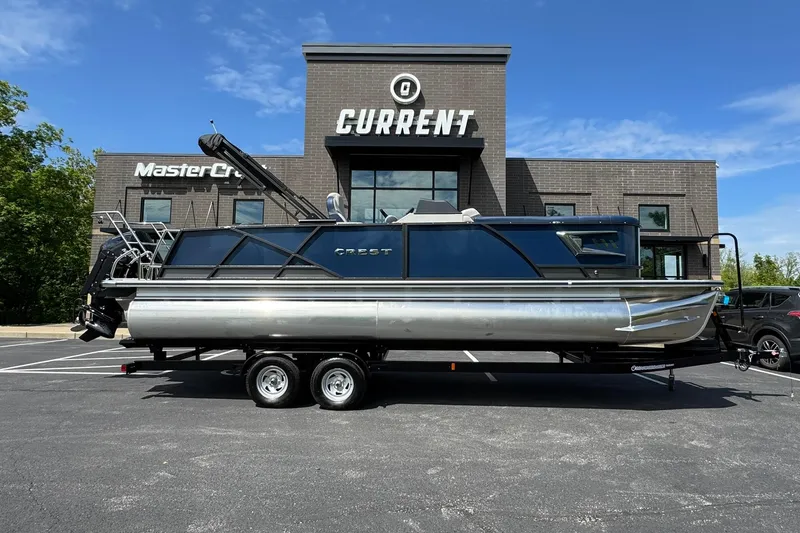 Slide: The Image of 2024 Crest Caribbean LX 230 pontoon boat on trailer, parked outside dealership. - 3