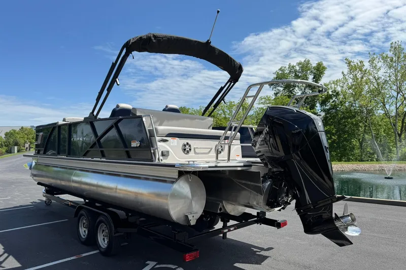 Slide: The Image of 2024 Crest Caribbean LX 230 pontoon boat on trailer, parked near a pond. - 6