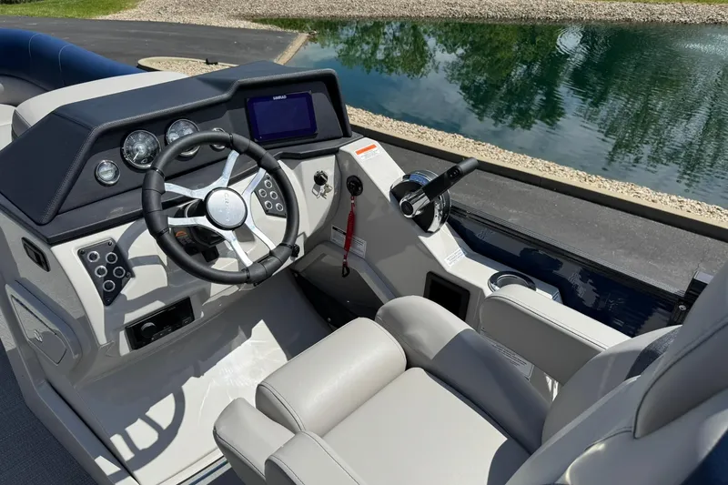 Slide: The Image of 2024 Crest Caribbean LX 230 boat cockpit with modern steering and controls by a serene lake. - 9