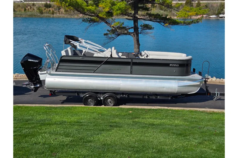 The Image of 2022 Crest Classic LX 220 SLRC pontoon boat on trailer by a lake. - 0
