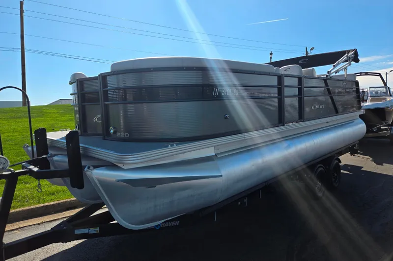 Slide: The Image of 2022 Crest Classic LX 220 SLRC pontoon boat on trailer under bright sunlight. - 5