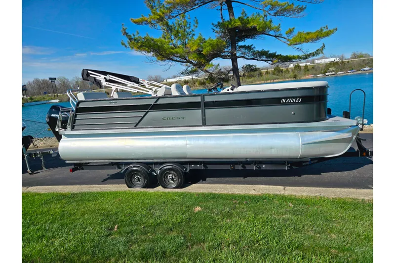 Slide: The Image of 2022 Crest Classic LX 220 SLRC pontoon boat on trailer by a lake. - 9