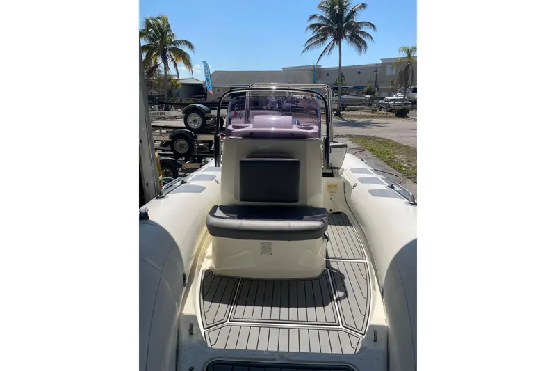 Slide: The Image of 2021 Brig Navigator 485 boat interior with seating and console, parked outdoors. - 2