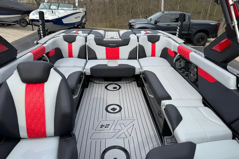 Slide: The Image of 2022 MasterCraft XT24 boat interior with red and gray seating, parked outdoors. - 11