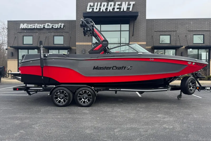 Slide: The Image of 2022 MasterCraft XT24 boat in red and gray, parked outside dealership. - 2