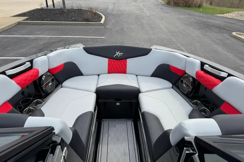 Slide: The Image of 2022 MasterCraft XT24 boat interior with red and gray seating, cup holders, and speakers. - 7