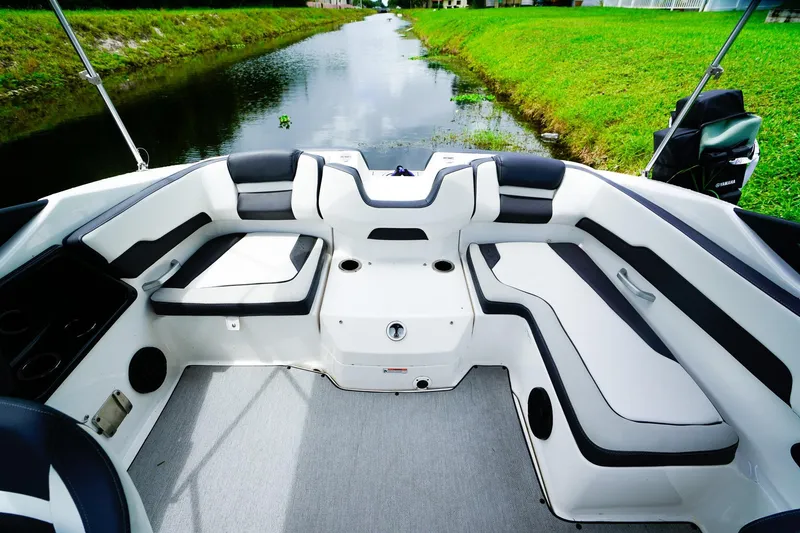 Slide: The Image of 2023 Yamaha Boats SX195 with sleek seating and deck design by the water. - 5