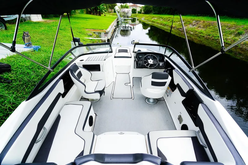 Slide: The Image of 2023 Yamaha Boats SX195 interior with sleek seating and modern design by a serene waterway. - 6