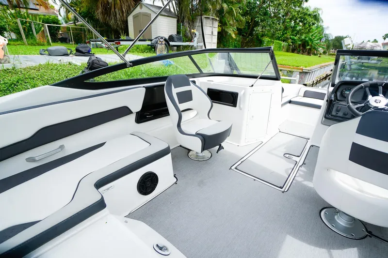 Slide: The Image of 2023 Yamaha Boats SX195 interior with sleek seating and modern steering, docked by a canal. - 7