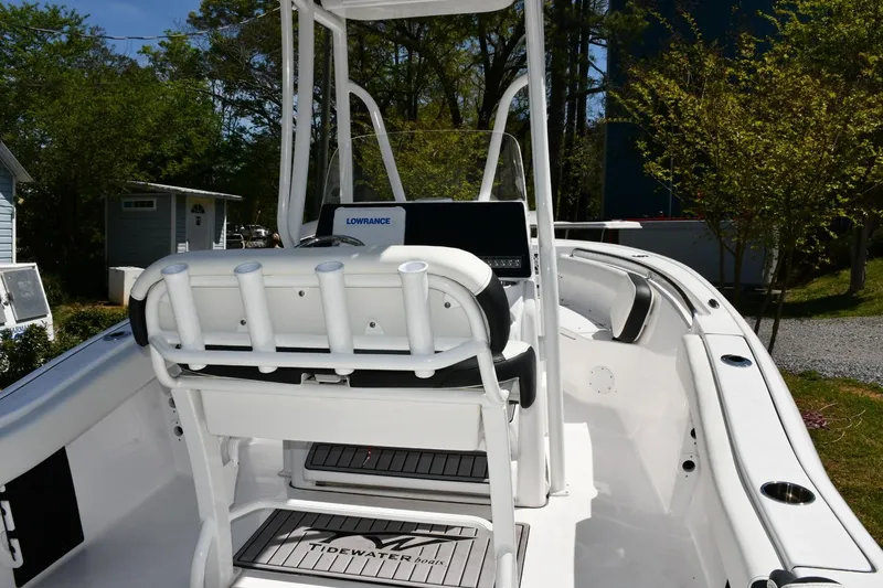 Slide: The Image of 2023 Tidewater 210 LXF boat interior with seating and console, surrounded by greenery. - 17