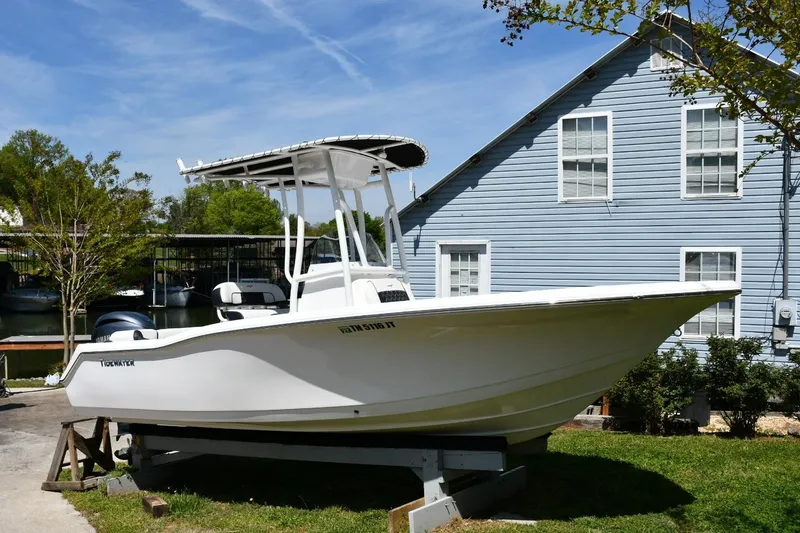 Slide: The Image of 2023 Tidewater 210 LXF boat displayed outdoors near a blue house. - 2