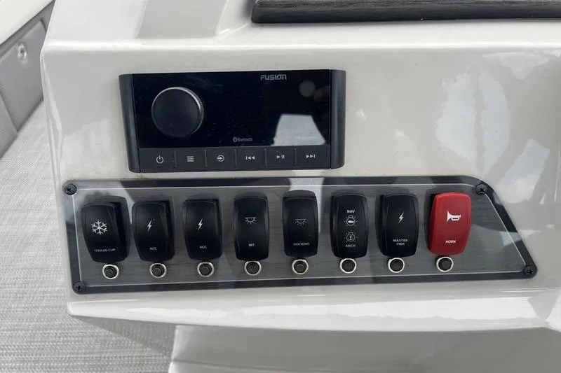 Slide: The Image of Control panel of 2024 Crest Classic Platinum 240 SLC boat with switches and audio system. - 13