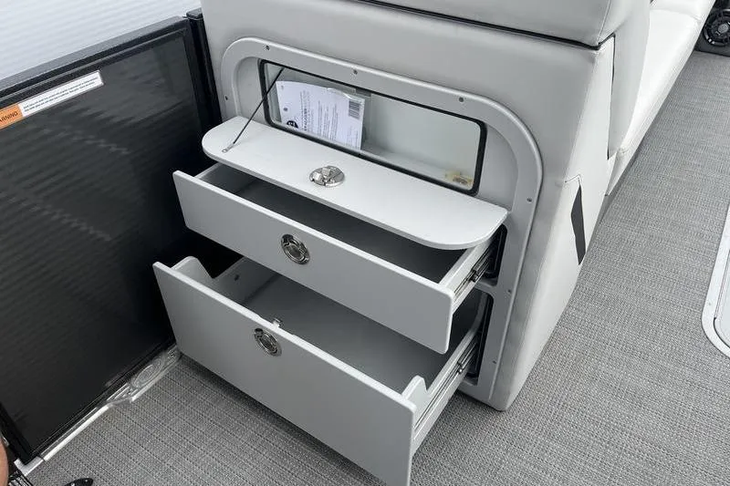 Slide: The Image of 2024 Crest Classic Platinum 240 SLC boat interior storage drawers open. - 16