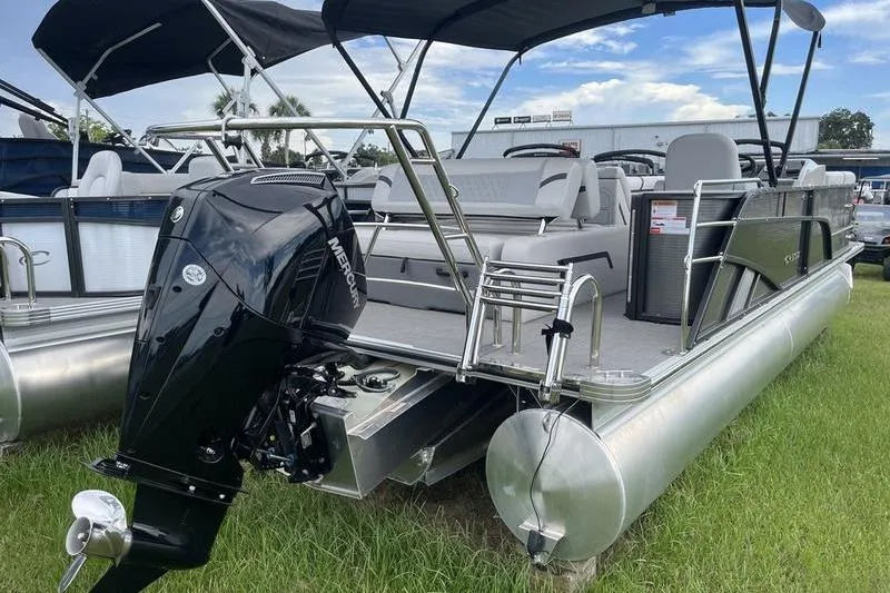 Slide: The Image of 2024 Crest Classic Platinum 240 SLC pontoon boat with Mercury outboard motor, parked on grass. - 3