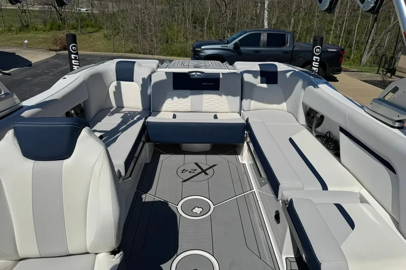 Slide: The Image of 2021 MasterCraft X24 boat interior with white and navy seating, parked outdoors. - 12
