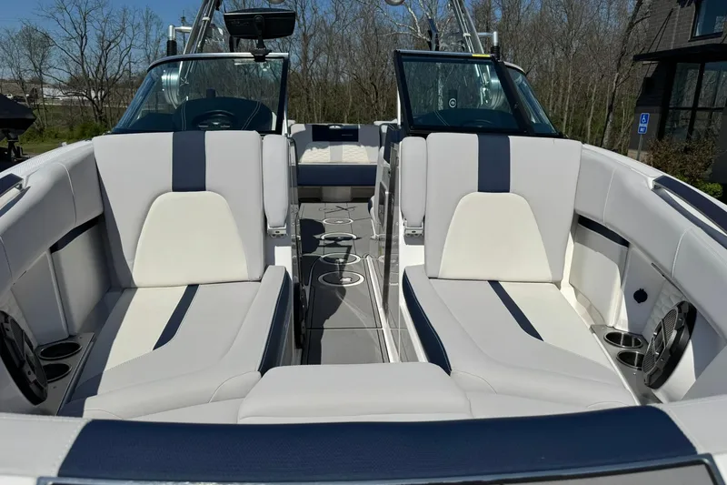 Slide: The Image of 2021 MasterCraft X24 boat interior with white and navy seating, cup holders, and steering console. - 7