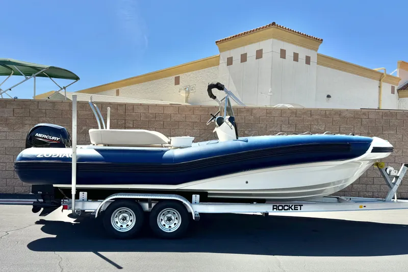 The Image of 2021 Zodiac N-ZO 680 boat on trailer, featuring Mercury engine, parked outdoors. - 0