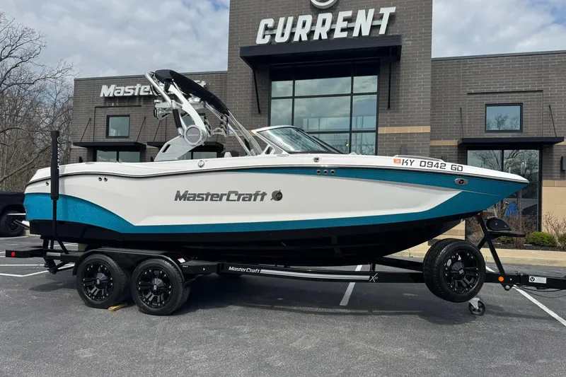 The Image of 2021 MasterCraft X22 boat on trailer, parked outside dealership, showcasing sleek design and modern features. - 1