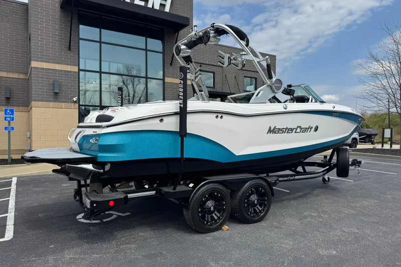 Slide: The Image of 2021 MasterCraft X22 boat on trailer, parked outside a modern building. - 3