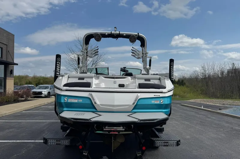 Slide: The Image of 2021 MasterCraft X22 boat, rear view, parked outdoors under a clear sky. - 4