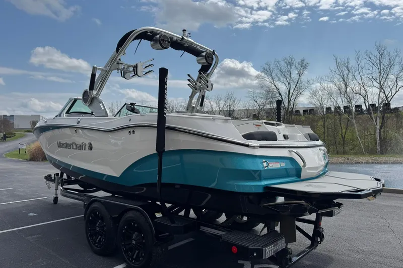 Slide: The Image of 2021 MasterCraft X22 boat on trailer, parked outdoors under a partly cloudy sky. - 5