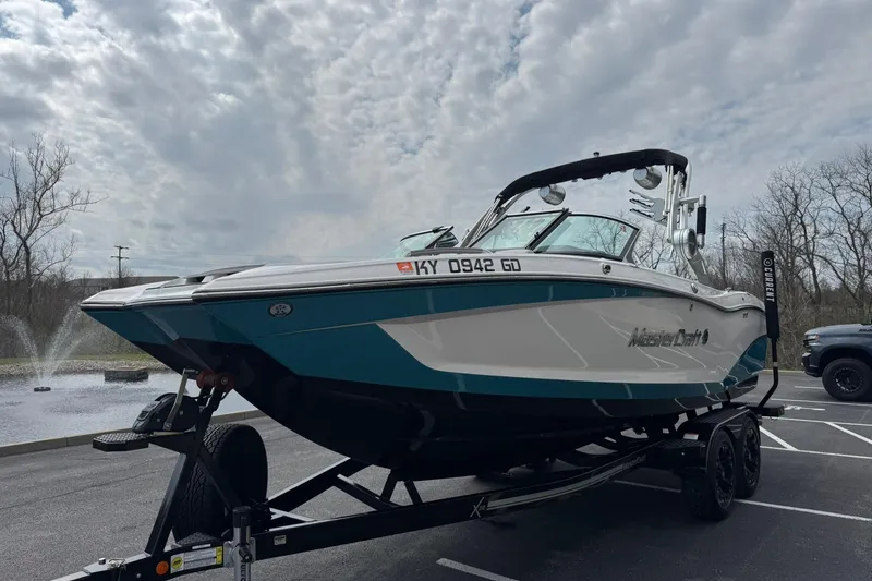 Slide: The Image of 2021 MasterCraft X22 boat on trailer, parked in lot under cloudy sky. - 6