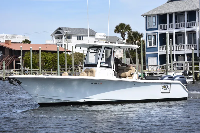 The Image of 2017 Sea Hunt Gamefish 27 boat with forward seating, docked near waterfront homes. - 1