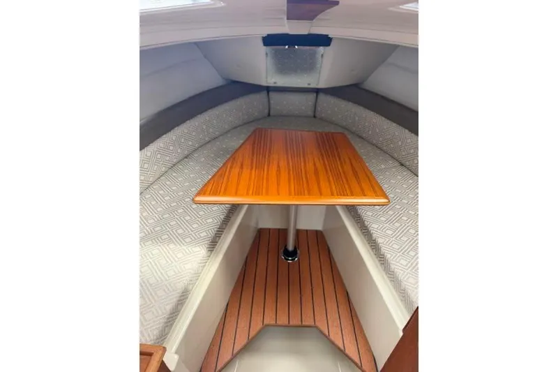 Slide: The Image of 2020 Ranger Tugs R-23 cabin interior with wooden table and cushioned seating. - 26