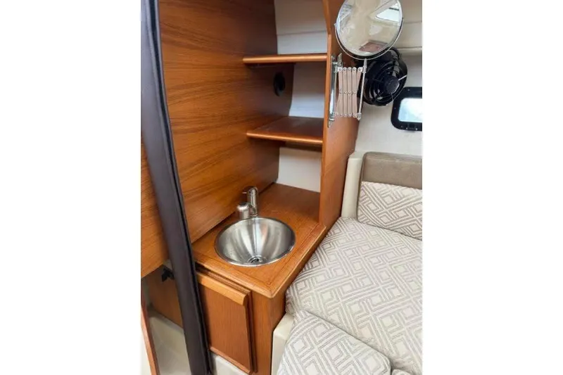 Slide: The Image of 2020 Ranger Tugs R-23 interior with wooden cabinetry, sink, and patterned seating. - 27