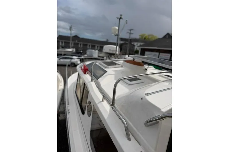 Slide: The Image of 2020 Ranger Tugs R-23 boat with rooftop railing and skylights, docked under cloudy skies. - 8