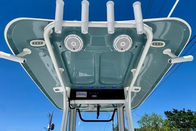 Slide: The Image of T-top of 2022 Sea Hunt BX 25 FS boat with rod holders and speakers against blue sky. - 11