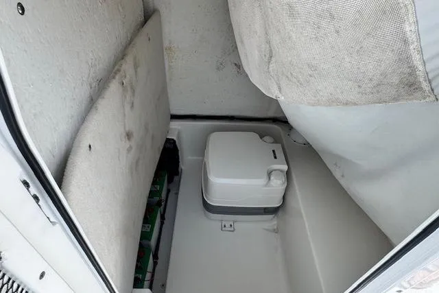 Slide: The Image of 2022 Sea Hunt BX 25 FS boat interior with portable toilet and storage area. - 13