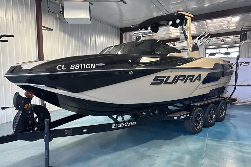 Slide: The Image of 2023 Supra SE 550 boat on trailer in indoor showroom. - 2