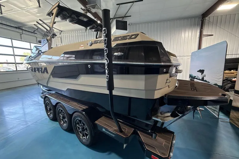 Slide: The Image of 2023 Supra SE 550 boat in showroom, featuring sleek design and triple-axle trailer. - 4