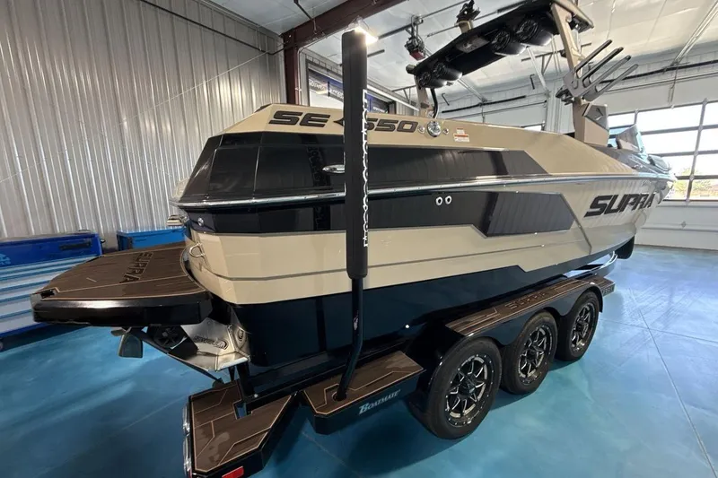 Slide: The Image of 2023 Supra SE 550 boat in showroom, featuring sleek design and triple-axle trailer. - 6