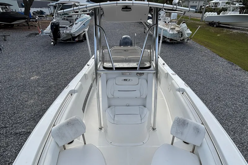 Slide: The Image of 2016 Sea Hunt Ultra 225 boat interior with seating and console, parked on gravel. - 8