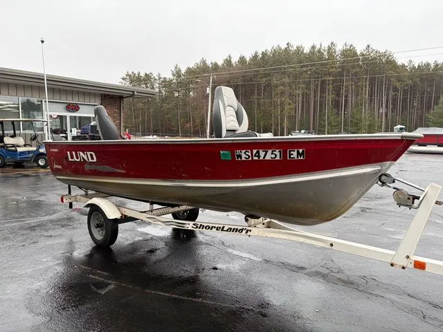 Slide: The Image of 1997 Lund 14 Rebel boat on trailer, red design, forest background. - 5