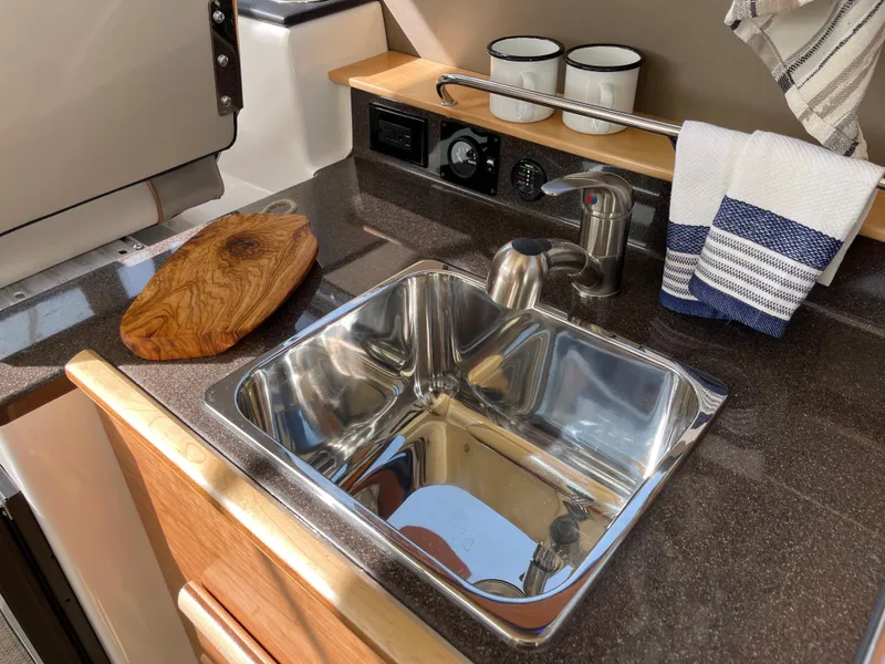 Slide: The Image of 2023 Cutwater C-288 boat kitchen sink with cutting board and striped towels - 38