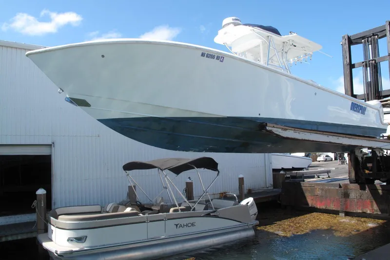 Slide: The Image of 2017 SeaVee 340B boat being lifted at a marina, with a Tahoe pontoon nearby. - 30