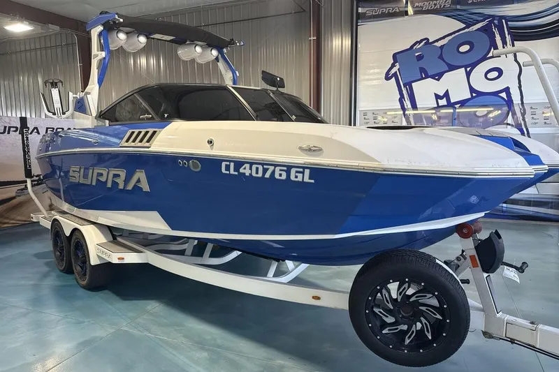 The Image of 2019 Supra SA 550 boat in showroom, blue and white design, on trailer. - 1