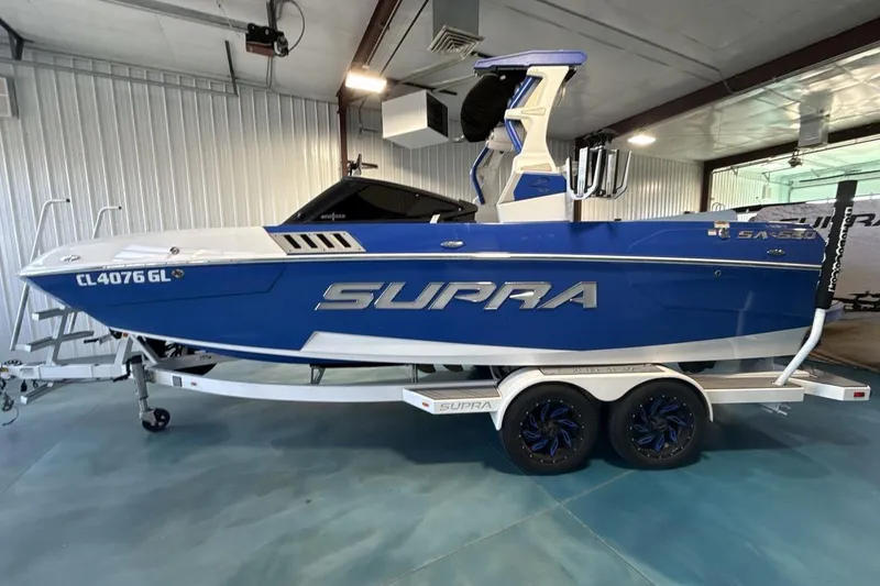 Slide: The Image of 2019 Supra SA 550 boat in blue, parked indoors on a trailer. - 3