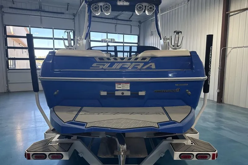 Slide: The Image of 2019 Supra SA 550 boat in a garage, showcasing its sleek blue design and swim platform. - 5