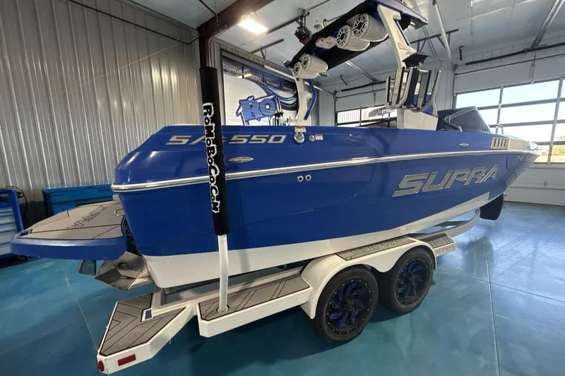 Slide: The Image of 2019 Supra SA 550 boat in a garage, blue exterior, on a trailer. - 6