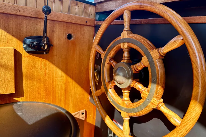 Slide: The Image of Wooden steering wheel and controls of a 1972 Fisher 30 boat, showcasing classic nautical design. - 25