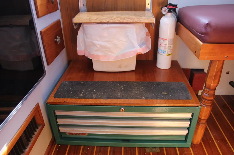 Slide: The Image of Interior of a 1972 Fisher 30 boat with storage, fire extinguisher, and wooden flooring. - 39
