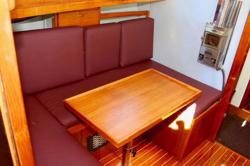 Slide: The Image of Cozy 1972 Fisher 30 boat interior with wooden table and maroon seating. - 41