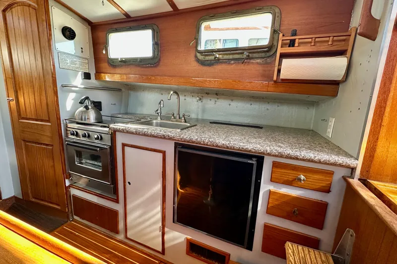 Slide: The Image of 1972 Fisher 30 boat kitchen with stove, sink, and wooden cabinetry. - 42