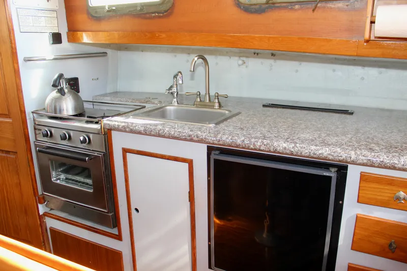 Slide: The Image of 1972 Fisher 30 yacht kitchen with stove, sink, and compact fridge. - 43